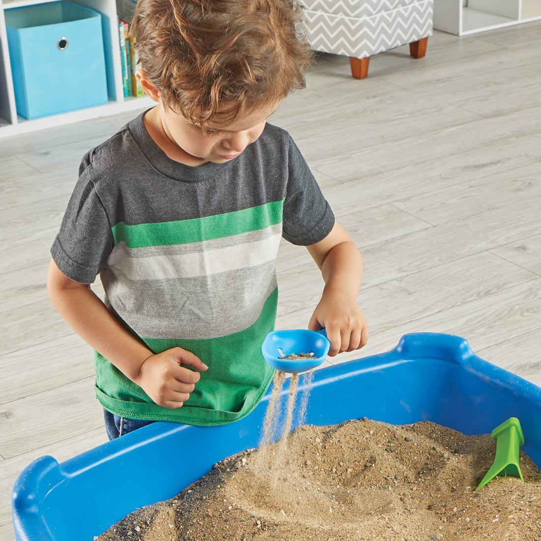 child using the Helping Hands Sensory Scoops with a bin of sand