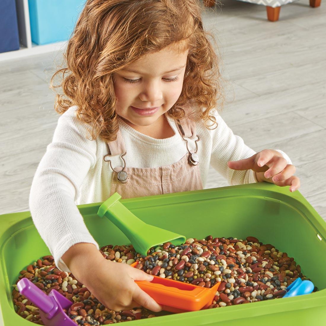 child using the Helping Hands Sensory Scoops with a bin of beans