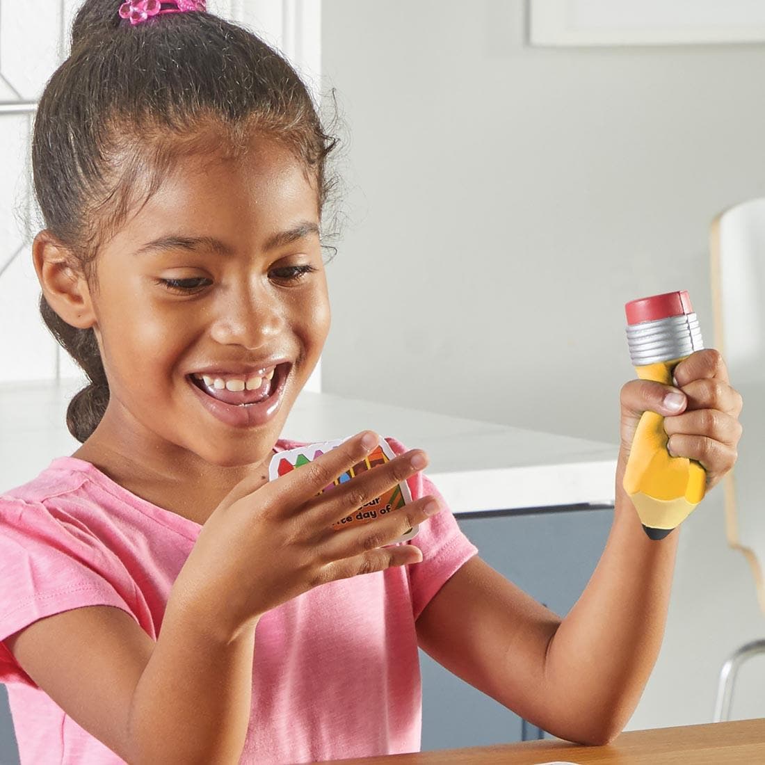 child holding a card and the foam pencil from Unpack Your Day Conversation Kit By Learning Resources