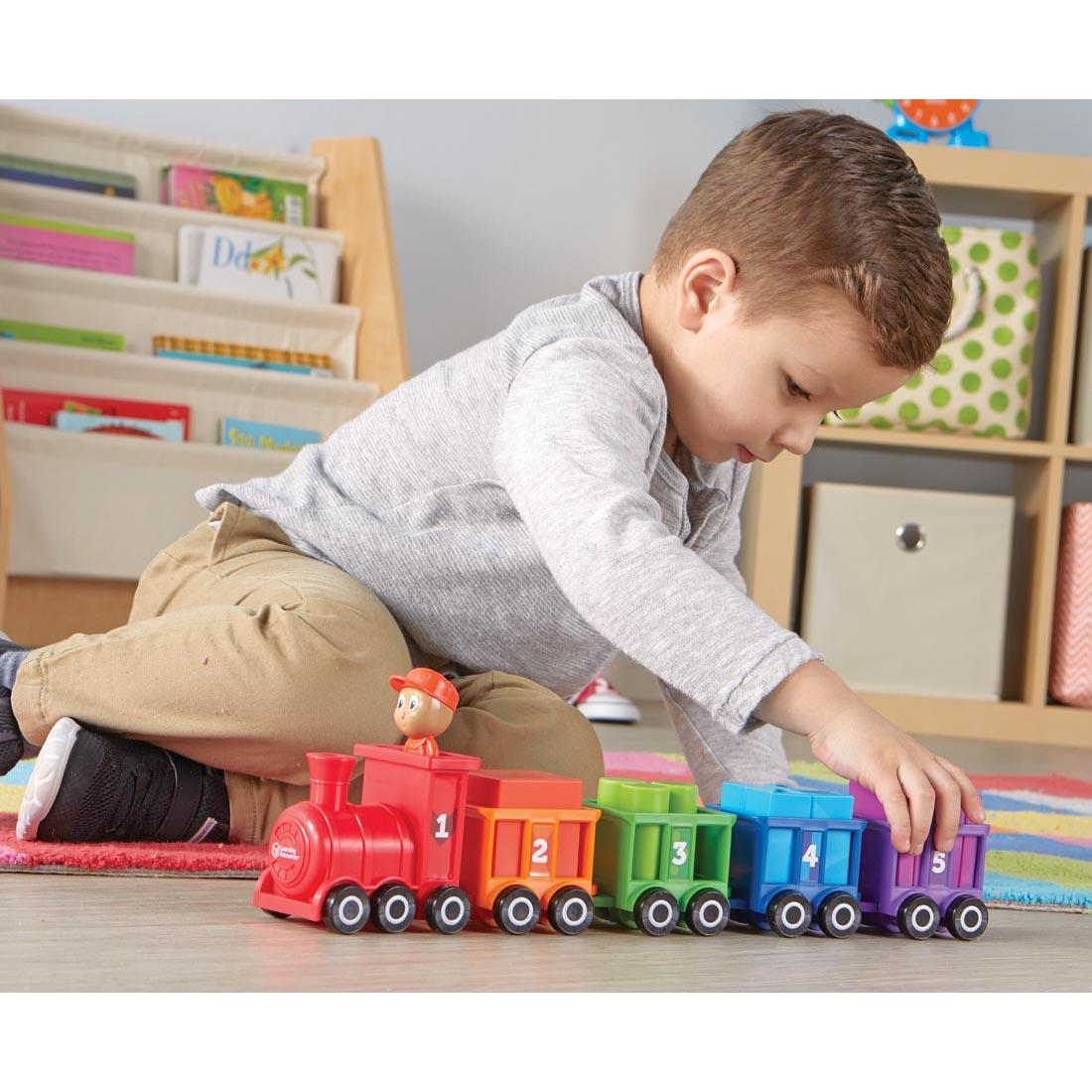 child playing with a train that has a car and cargo for each color and number