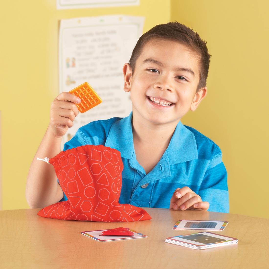 child pulling a Teaching Tac-Tile out of the bag, with activity cards