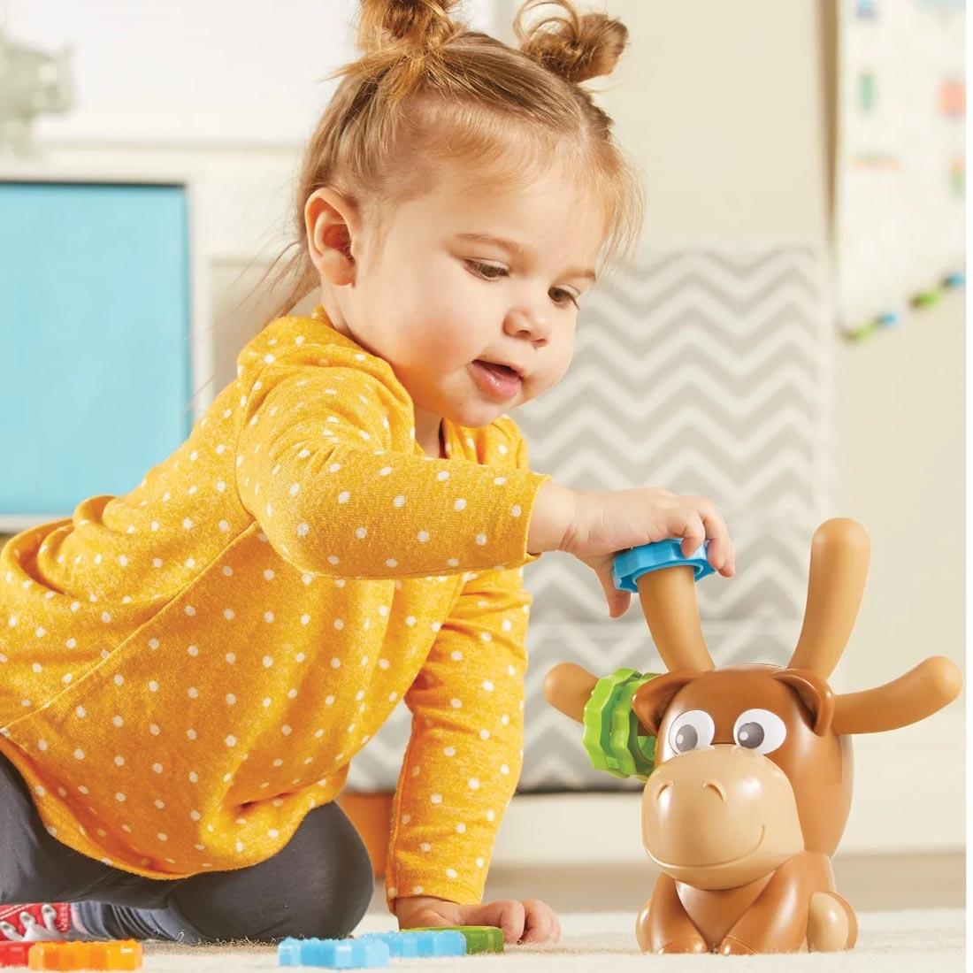 child placing a ring onto Max the Fine Motor Moose's antler