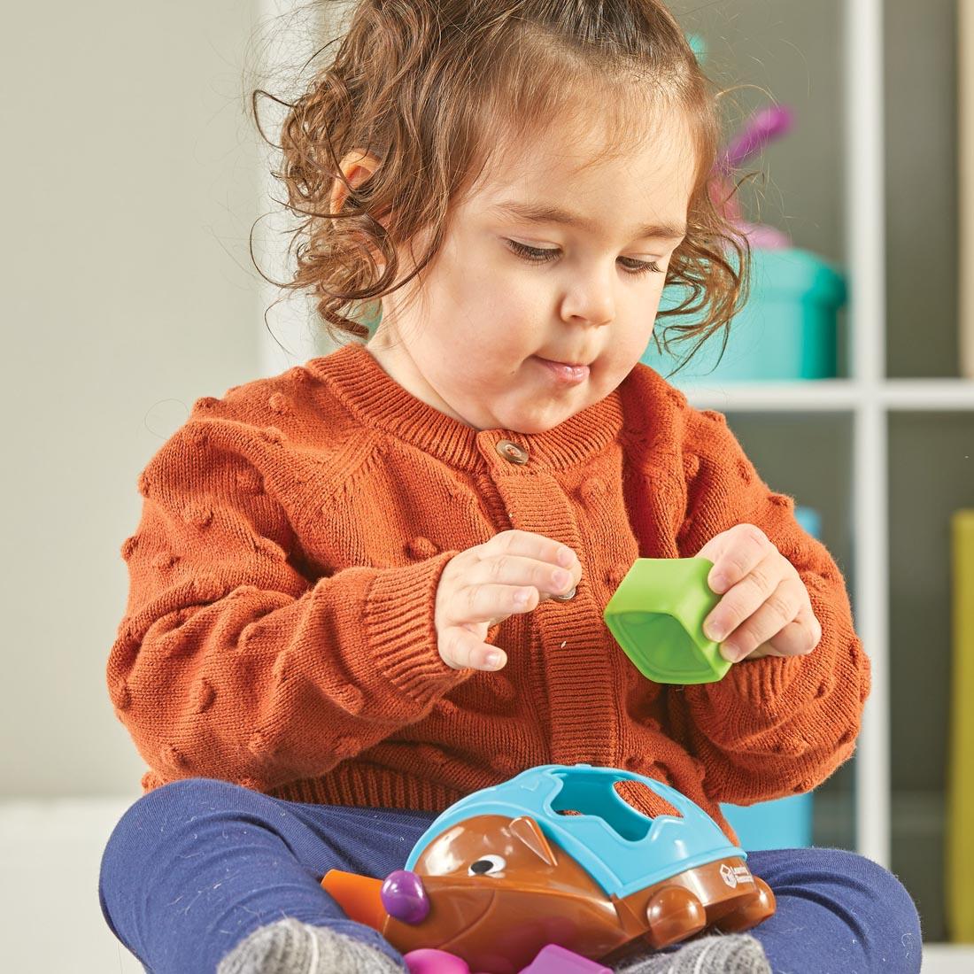 child playing with Spike The Fine Motor Hedgehog Poppin' Shapes Sorter