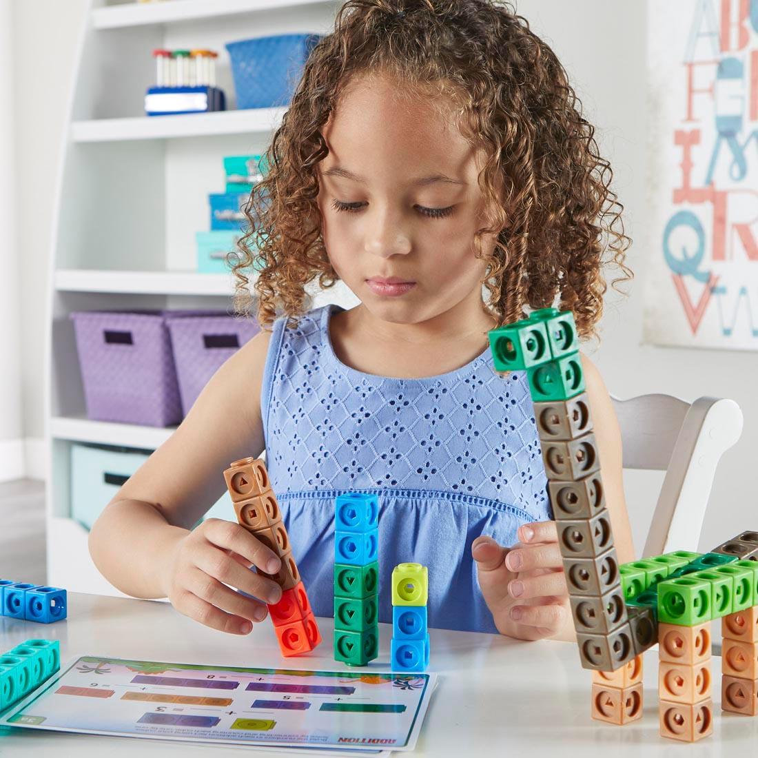 Child working with cubes and activity cards from the MathLink Cubes Kindergarten Math Activity Set: Dino Time! By Learning Resources