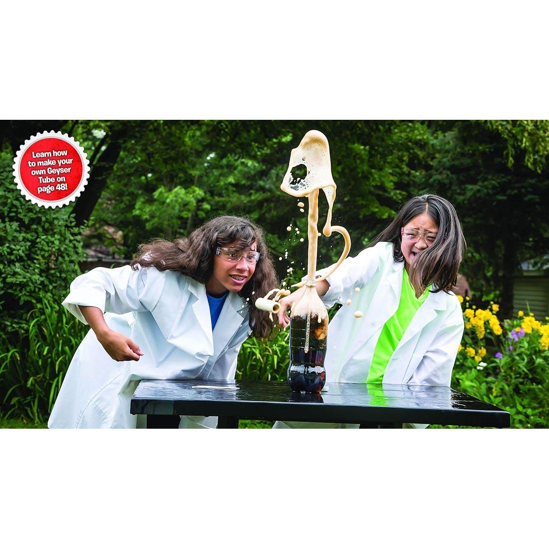 2 girls with an exploding geyser tube, with the words: Learn how to make your own geyser tube on page 48!