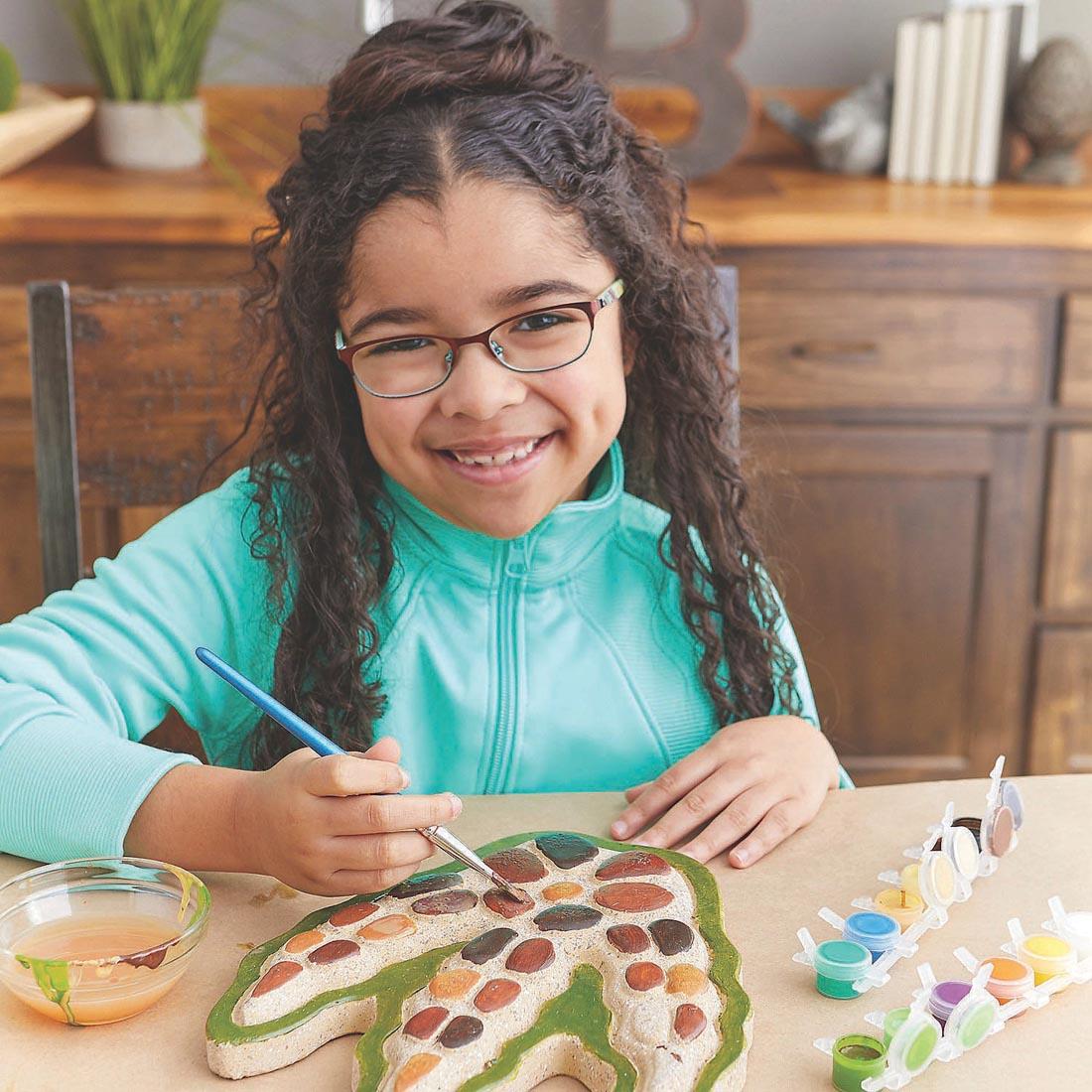 Child working on the Paint Your Own Stepping Stone Dinosaur Footprint Kit