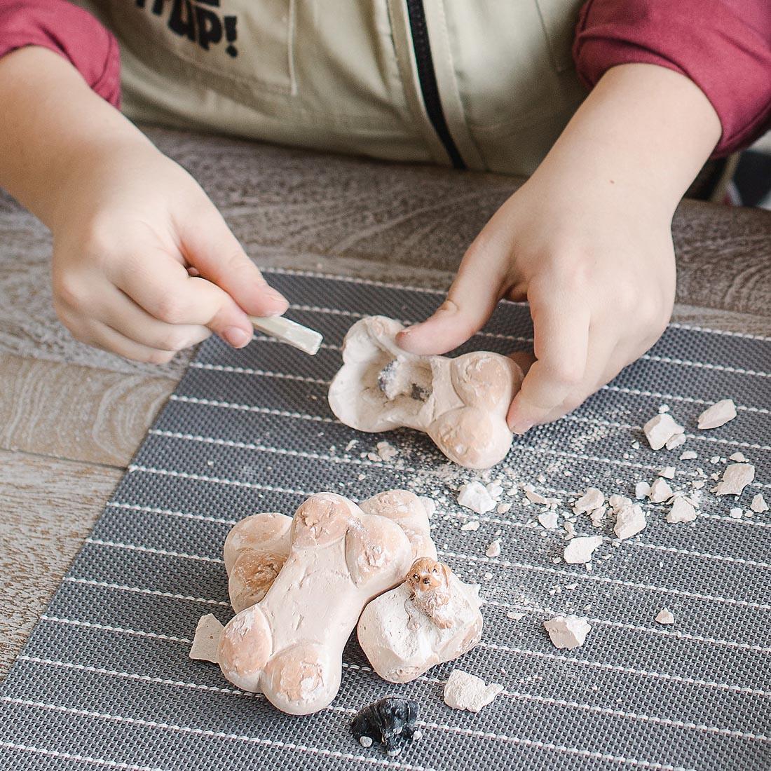 Child's hands holding a bone from the Dig It Up! Discoveries Puppies By Mindware