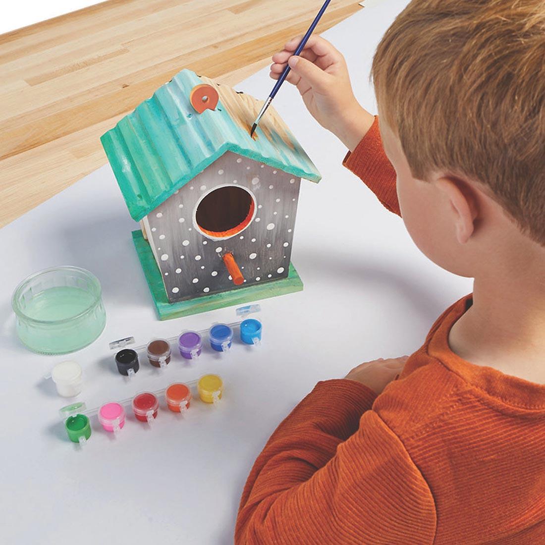 Child painting the Make Your Own Birdhouse Kit