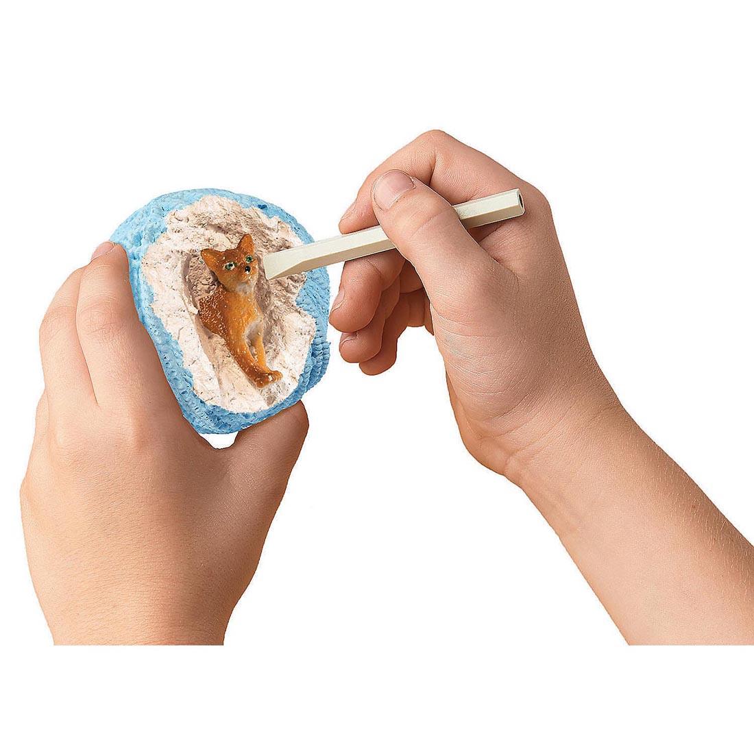 hands digging out a cat from the Dig It Up! Discoveries Cats By Mindware