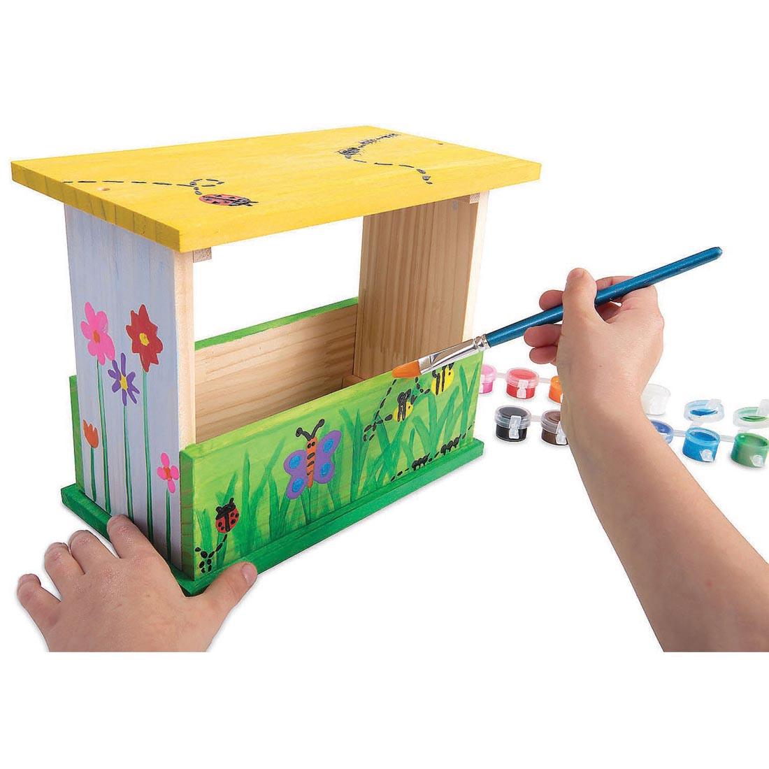 Hands painting the Make Your Own Bird Feeder Kit