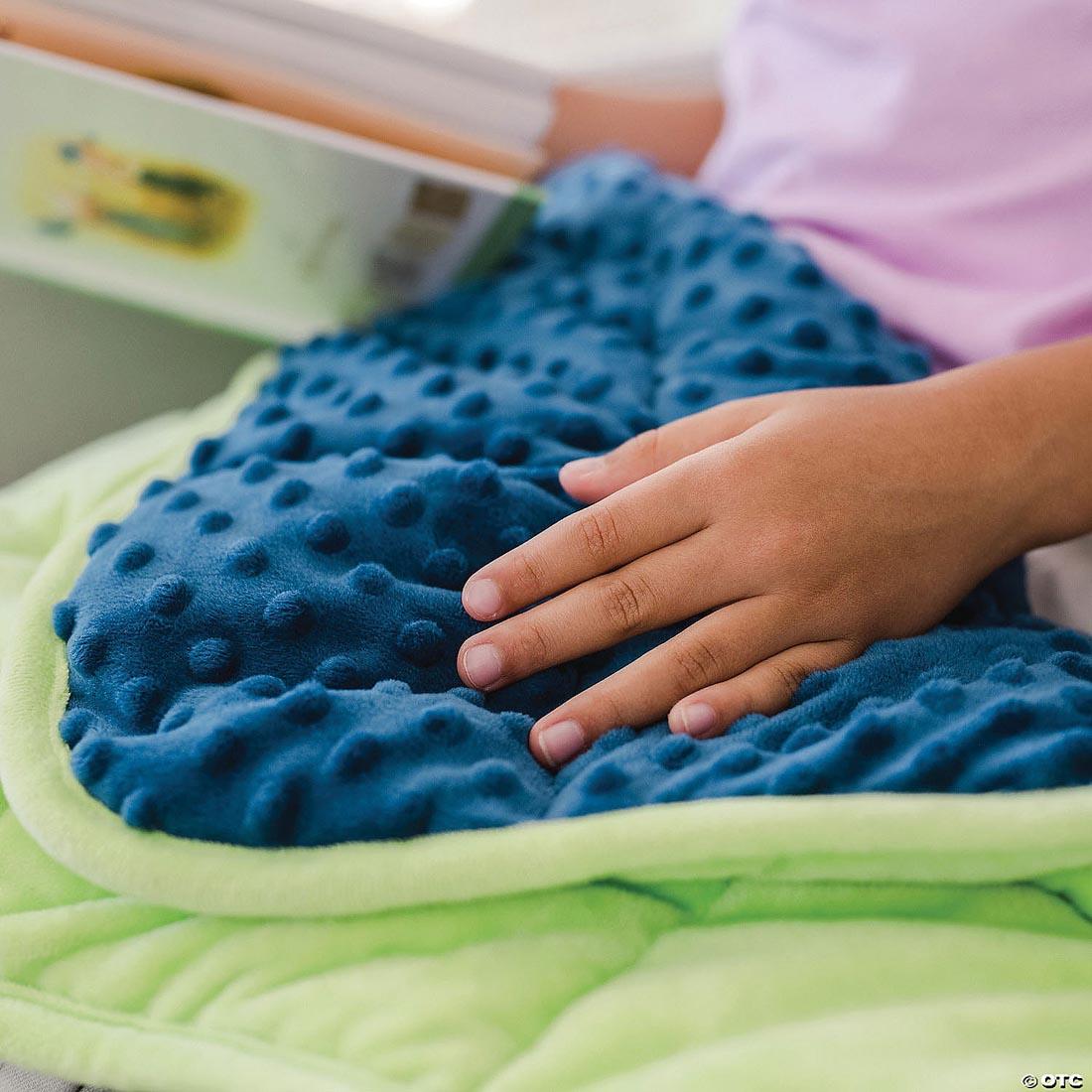 child hand on top of Sensory Genius Weighted Lap Pad