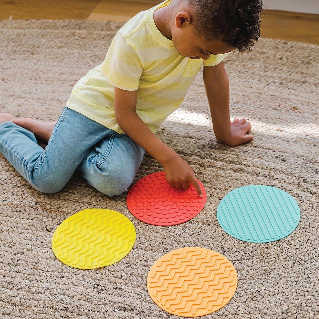 child sitting on the floor touching a Sensory Genius Sensory Mat By Mindware