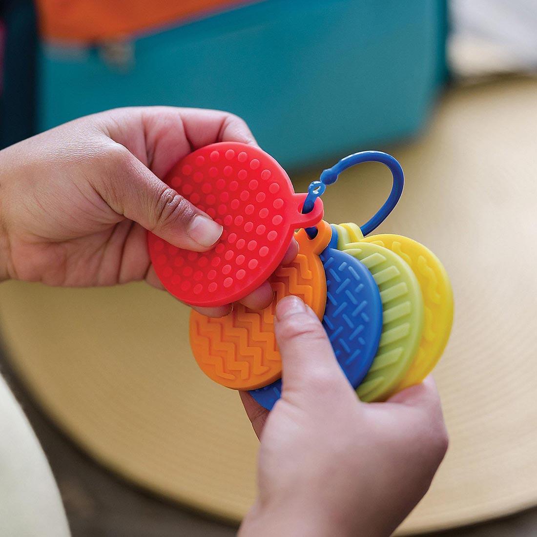 child's hands playing with sensory mats on a clip from the Sensory Genius Fun & Focus Pack Textures Fidget Toy Set By Mindware