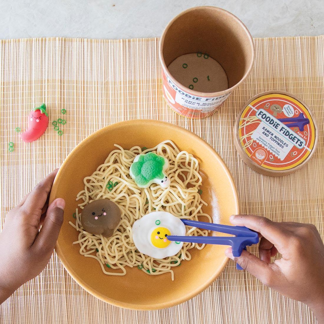 child playing with contents of Foodie Fidgets Ramen Noodles and Toppings, looking down in the bowl from the top