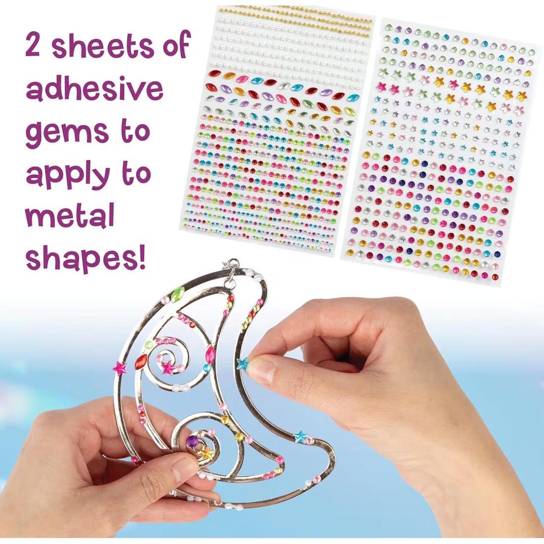 sticker sheets from the Make Your Own Suncatcher Kit By Mindware plus hands holding a suncatcher and text 2 sheets of adhesive gems to apply to metal shapes!