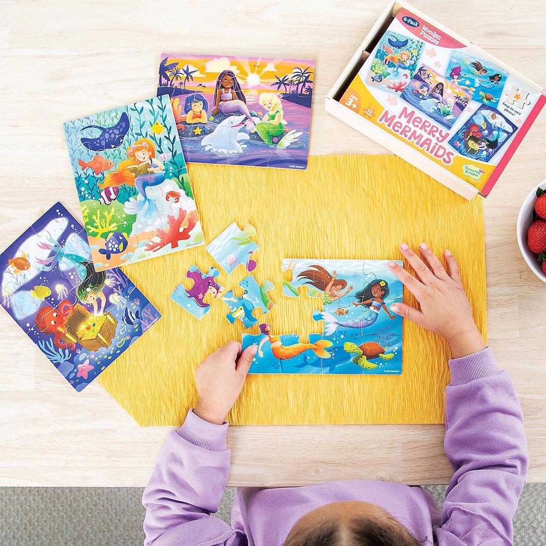 view from above of child completing puzzles from the Merry Mermaids Wooden Puzzles 4-Pack By Peaceable Kingdom
