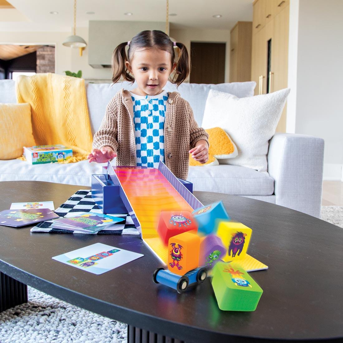 Girl playing with the Crash Monsters game, showing a foam monster block on a skateboard knocking down a stack of foam monster blocks