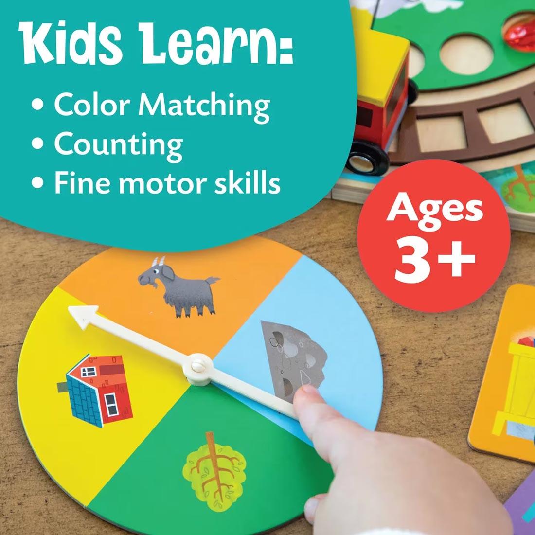 hand pointing to the spinner from Round the Mountain Cooperative Train Game By Peaceable Kingdom plus text Kids learn: color matching; counting; fine motor skills; Ages 3+