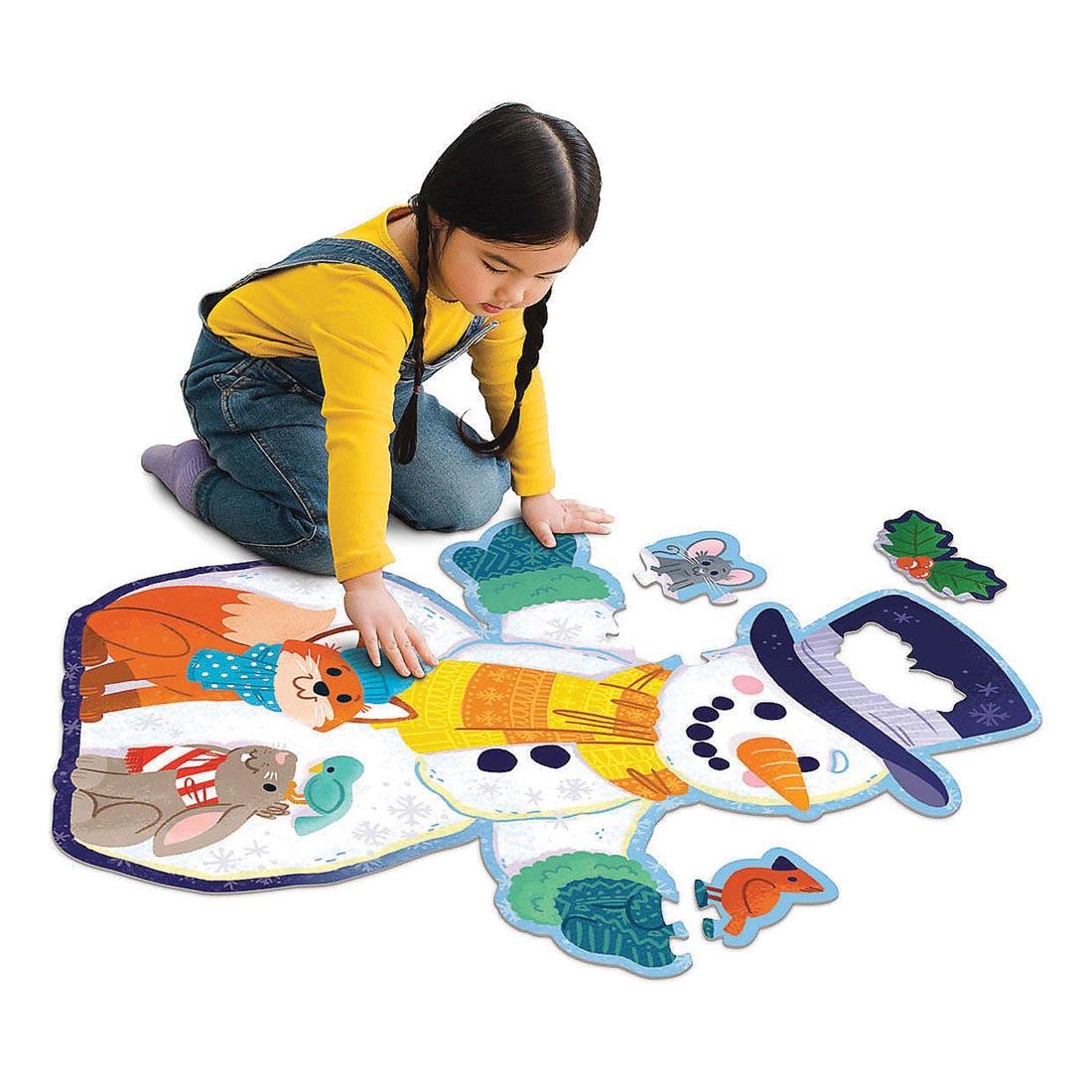 Child completing the Shimmery Snowman Floor Puzzle by Peaceable Kingdom