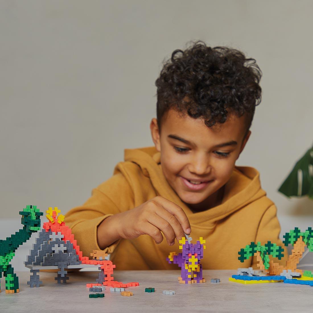 child playing with creations made with the Plus-Plus Learn To Build Dinosaurs Set