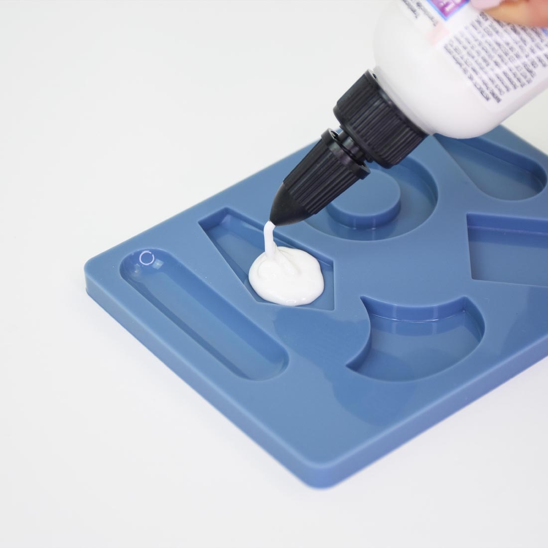 liquid sculpey being squeezed from a bottle into a mold