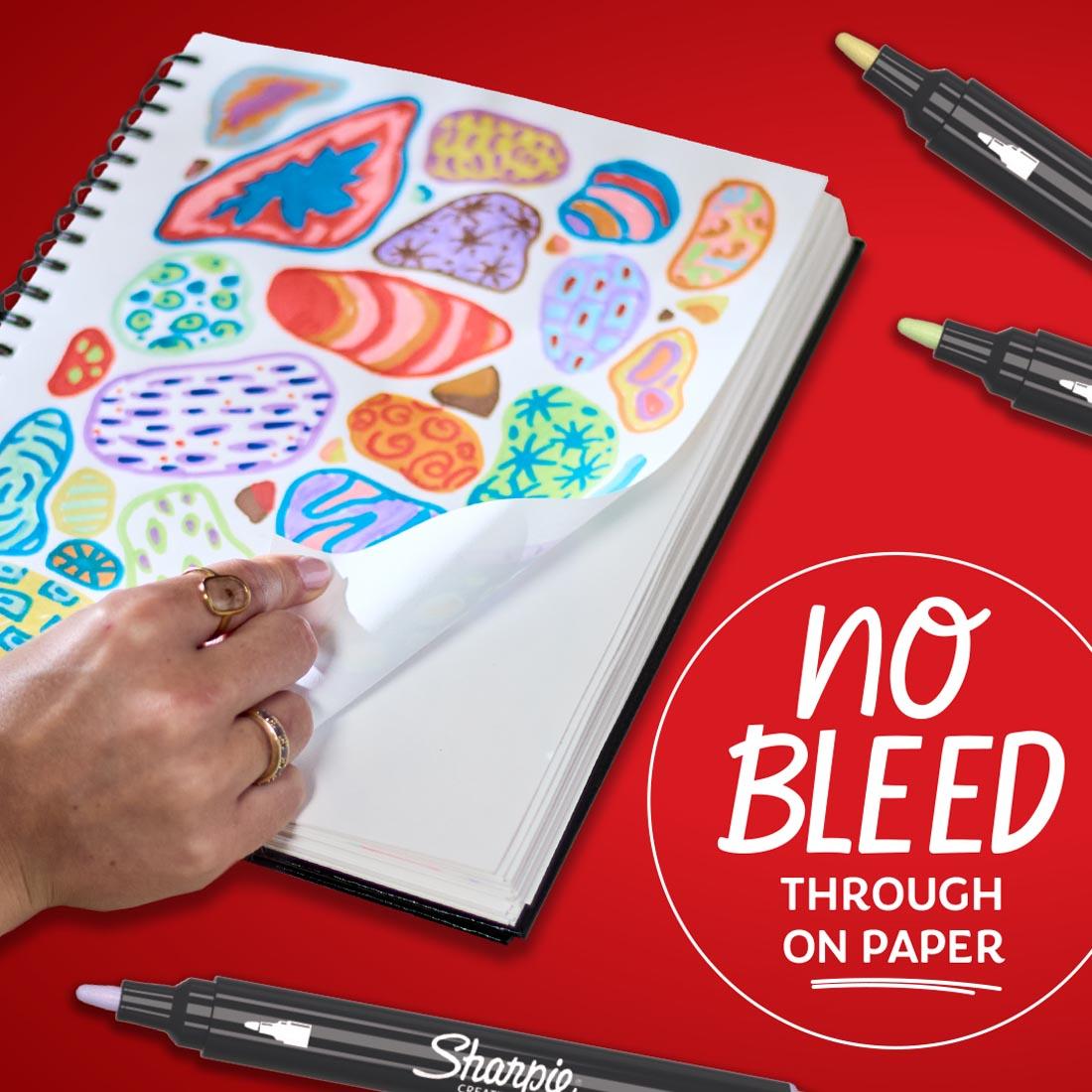 hand turning over a page with a colorful design drawn with Sharpie Creative Markers plus text No bleed through on paper