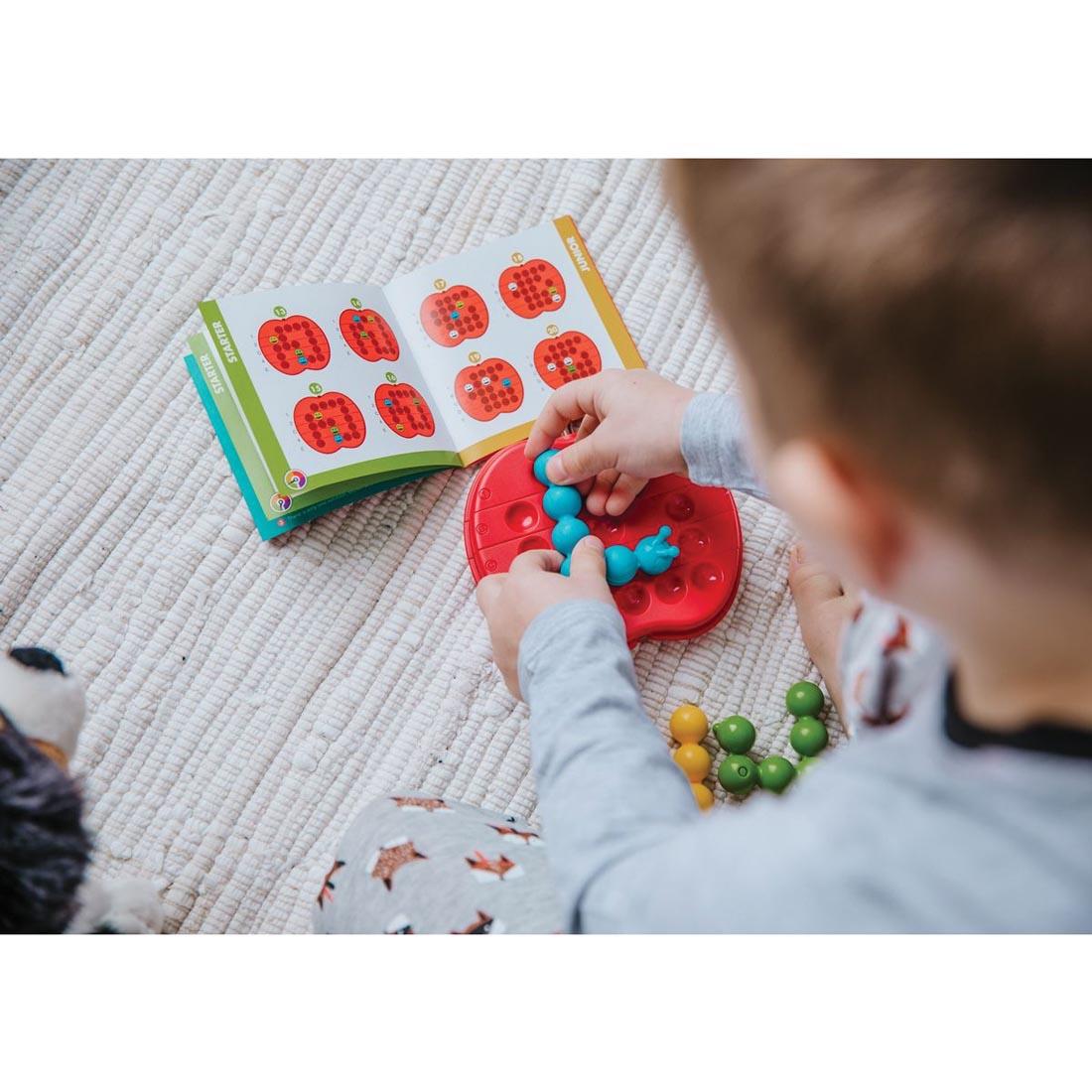 Child using the book to work on the Apple Twist Puzzle Game