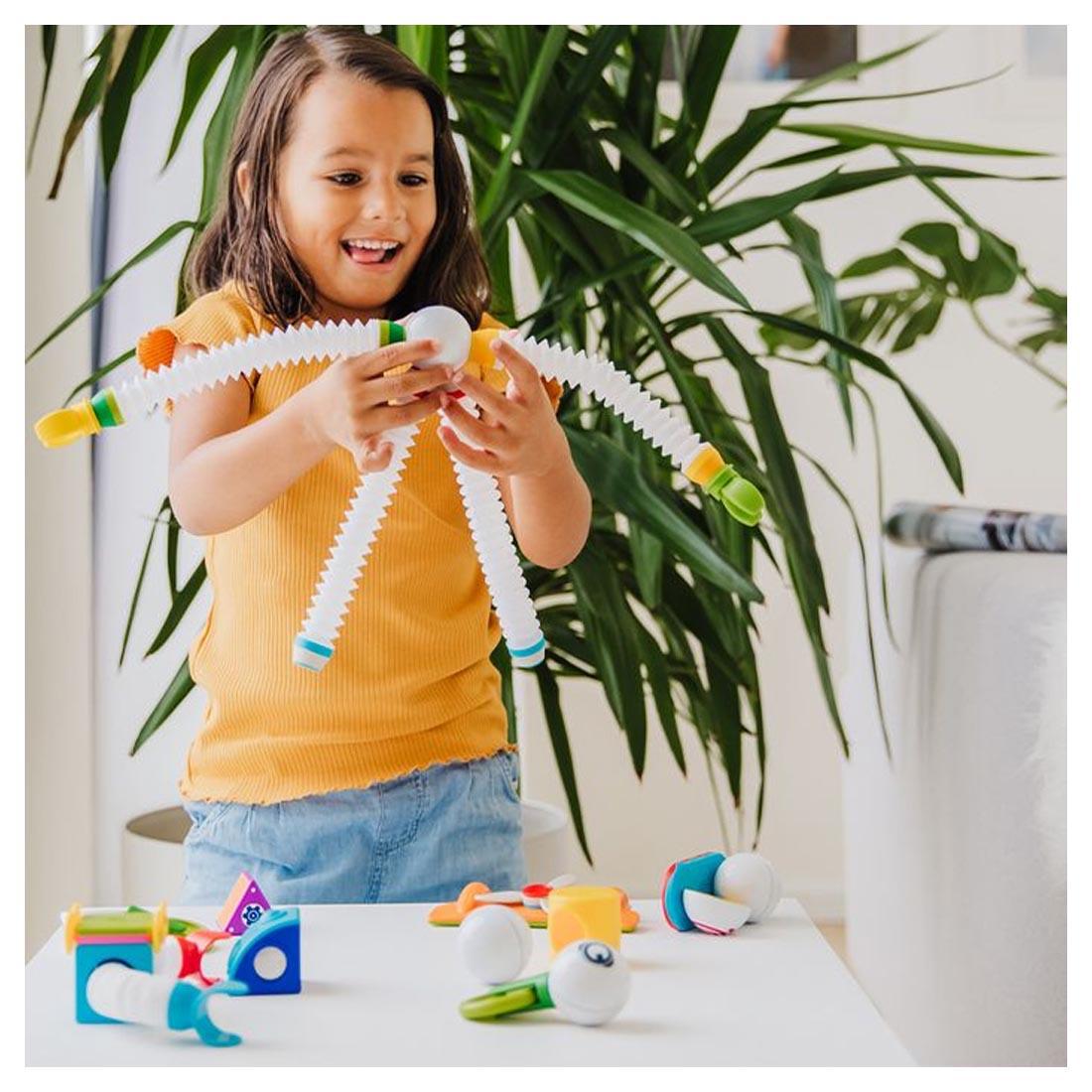 Child playing with the SMARTMAX Roboflex Plus Set with a tall houseplant in the background