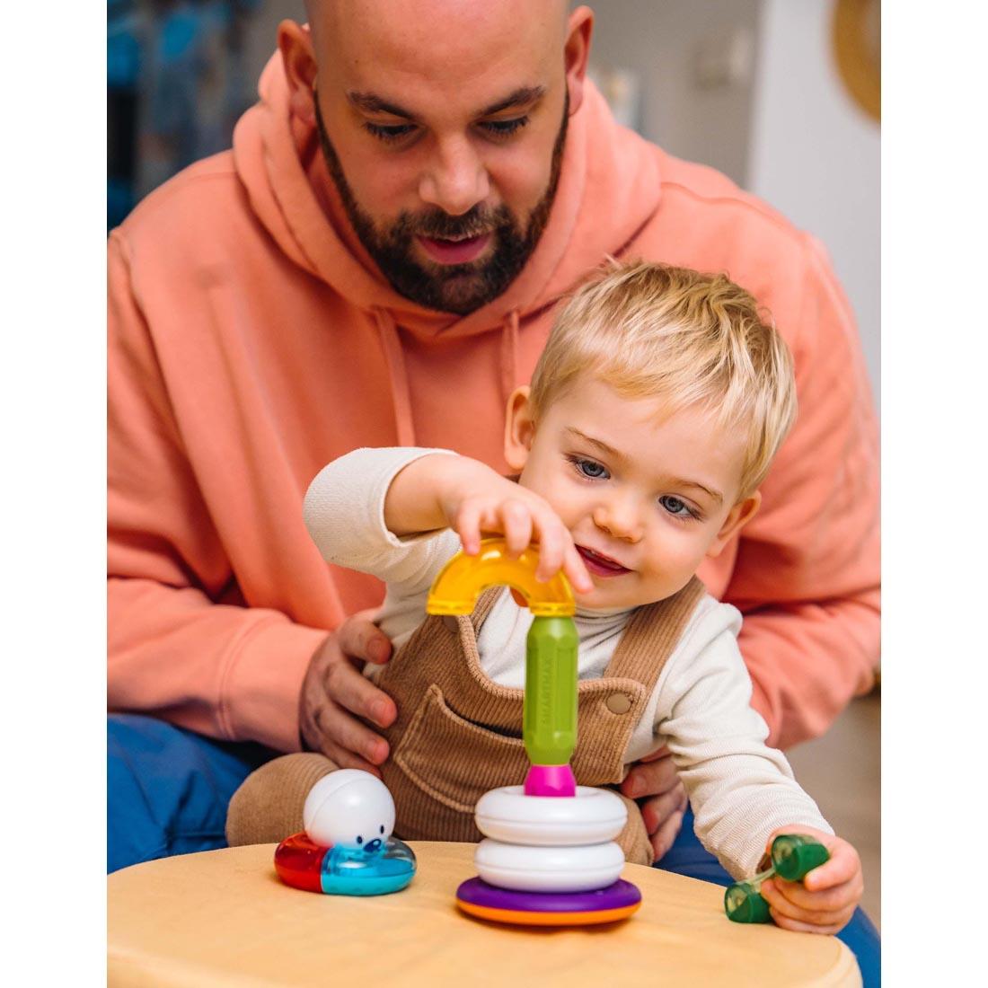 adult holding a child that's playing with SMARTMAX My First Stacking Rings