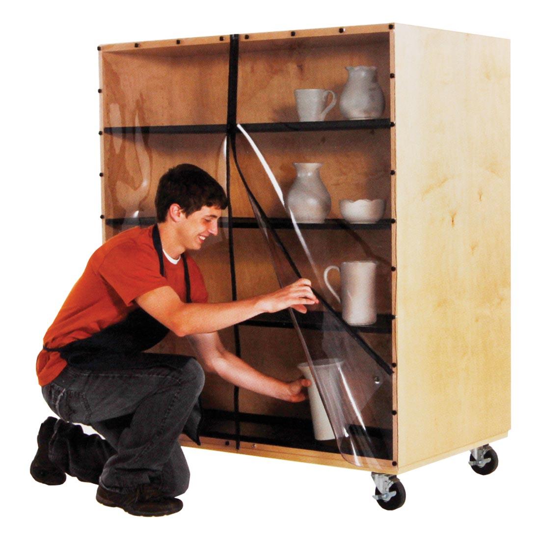 Person kneeling down to put pottery in Ware Cart