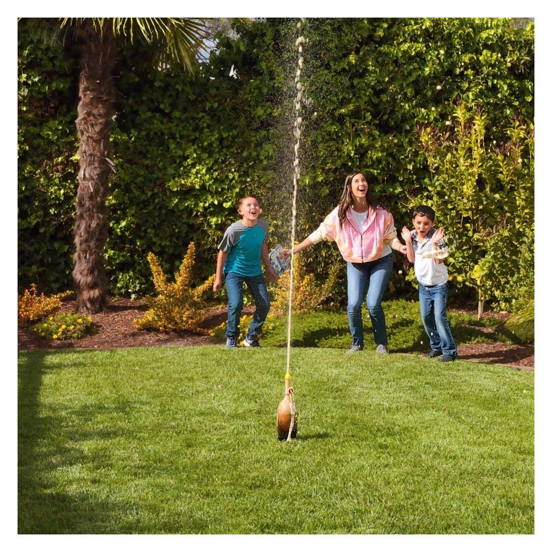 People in a yard watching cola erupt using the Geyser Tube Set By Steve Spangler Science