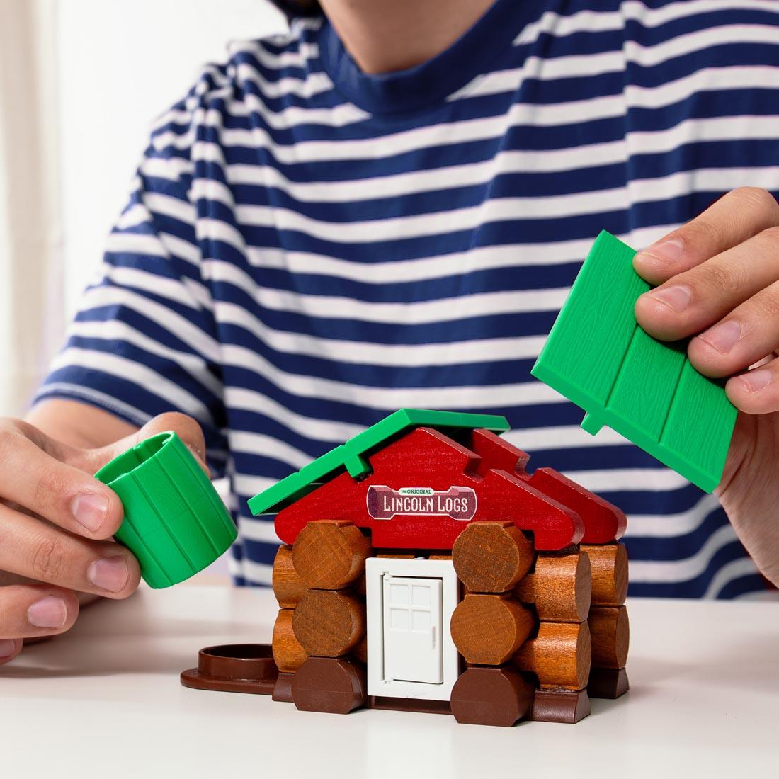 child's hands using the Lincoln Logs Mini Home Building Set