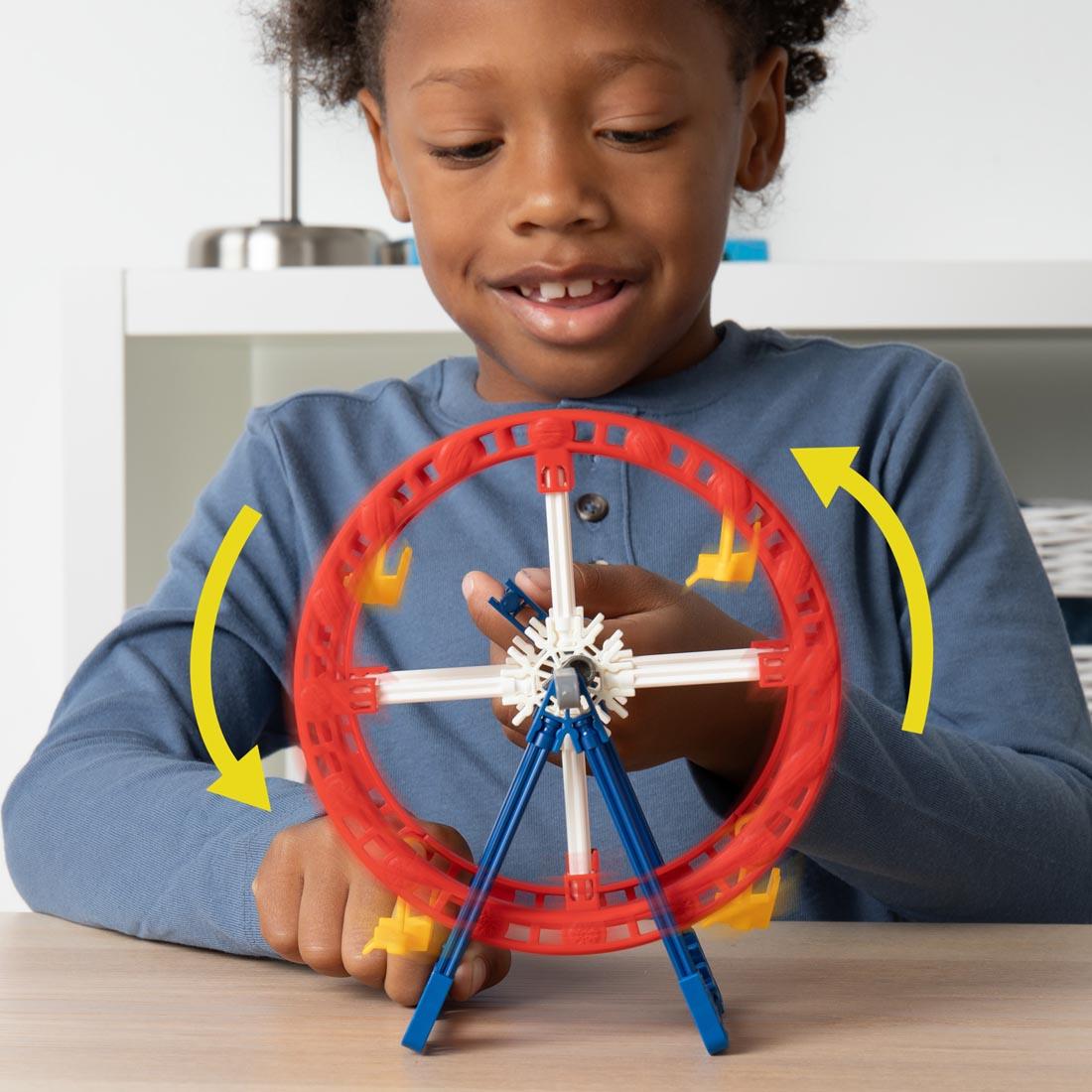 child turning a completed K'nex Mini Ferris Wheel with directional arrows drawn