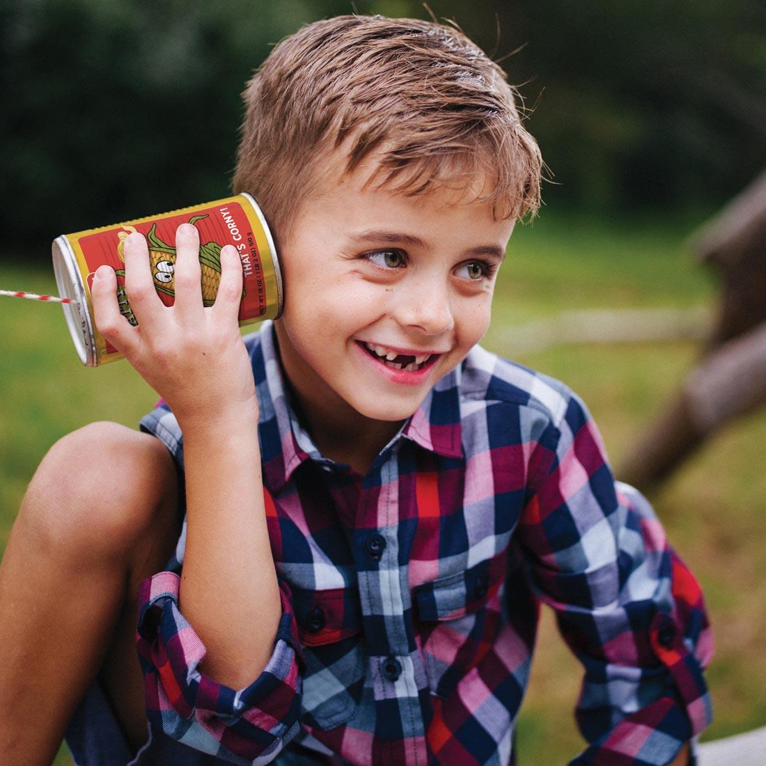 child holding one end of the Tin Can Telephone to their ear