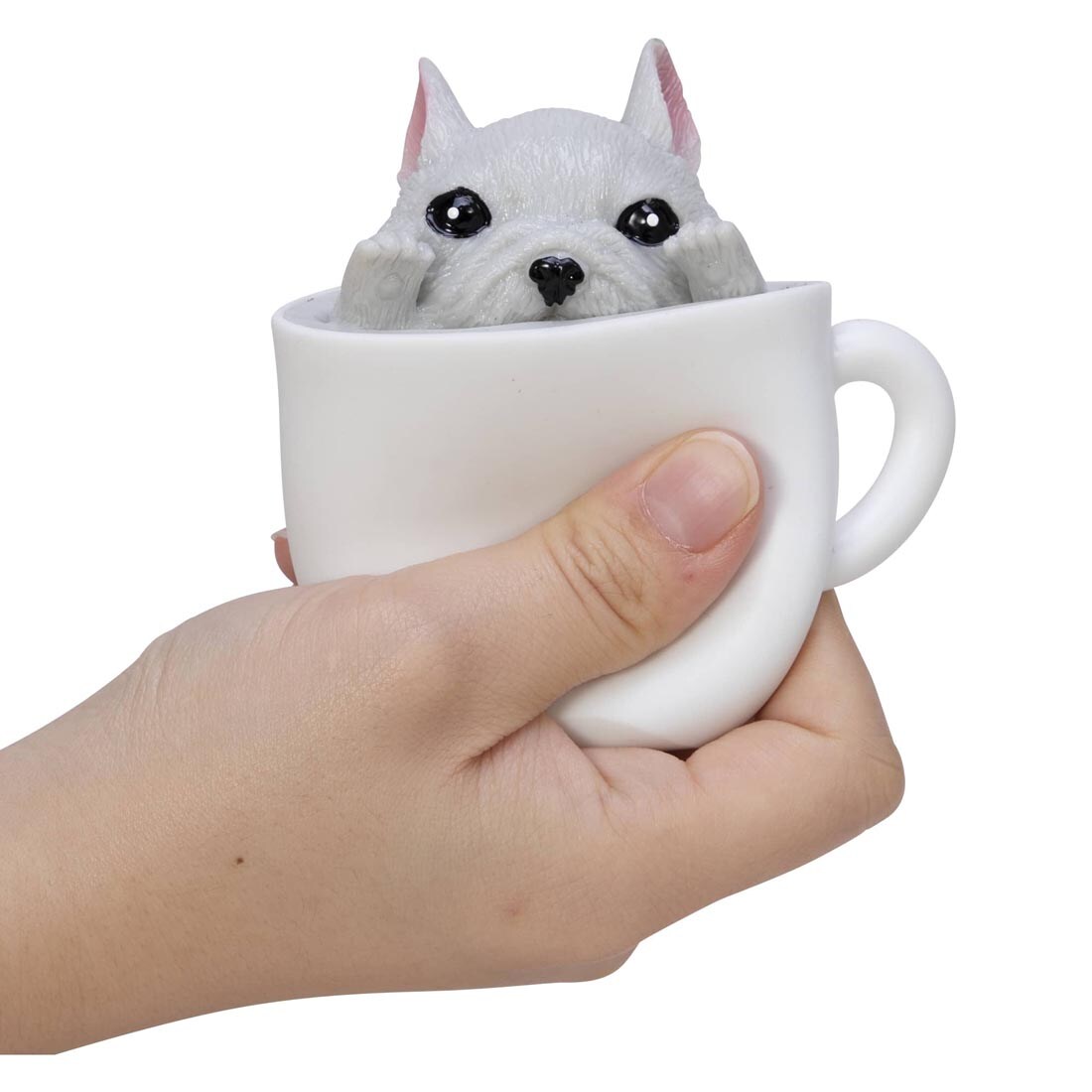 Hand squeezing a Pup In A Cup Squishy Toy By Schylling Toys