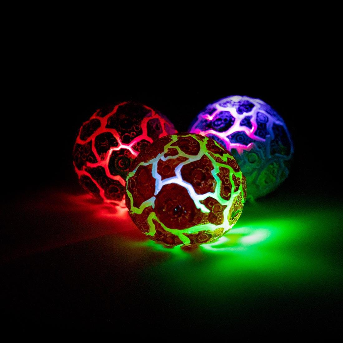 Three Magma Light Up Squeeze Balls illuminating the dark