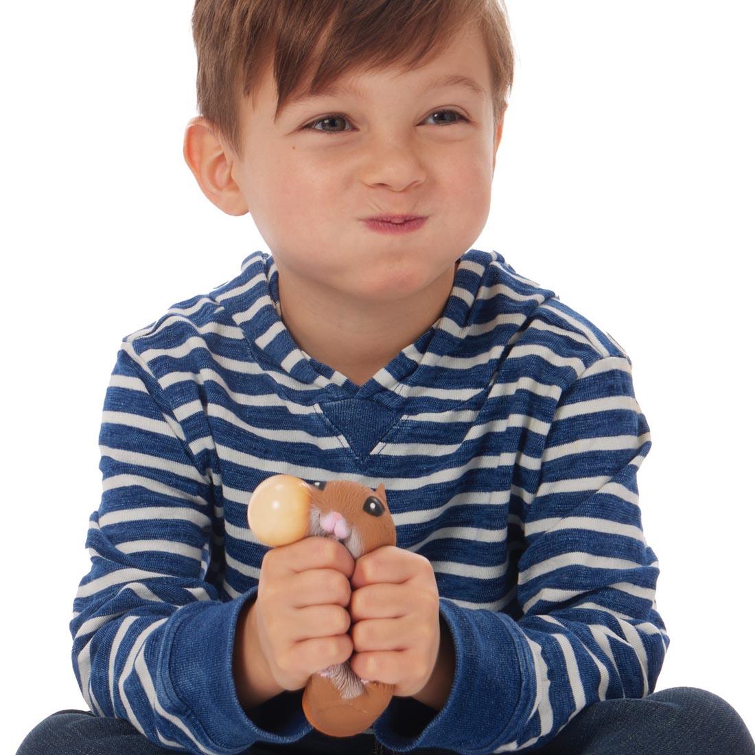 child puffing their cheeks while squeezing a Chonky Cheeks Hamster By Schylling Toys