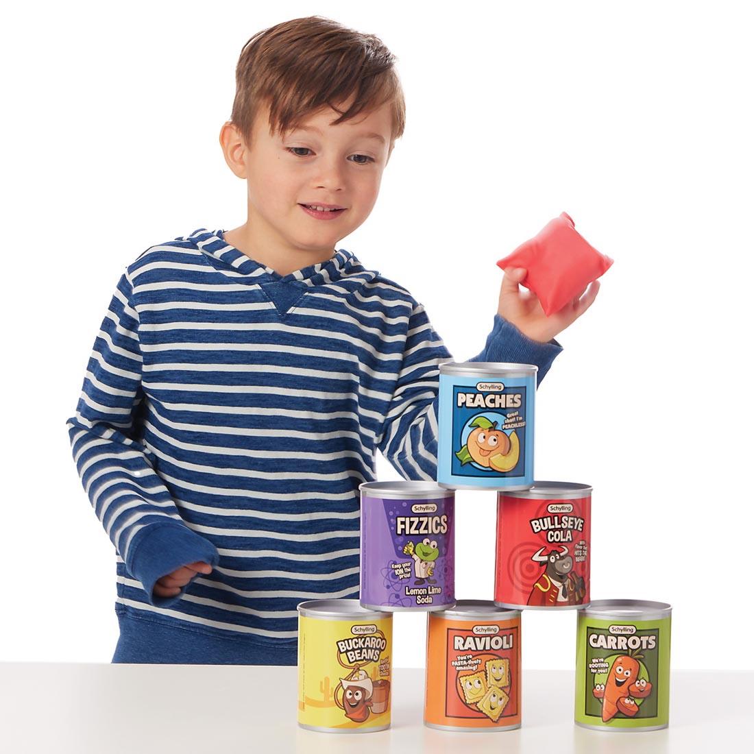 child holding a bean bag, aiming it at the cans from the Stack 'N Toss Set By Schylling Toys