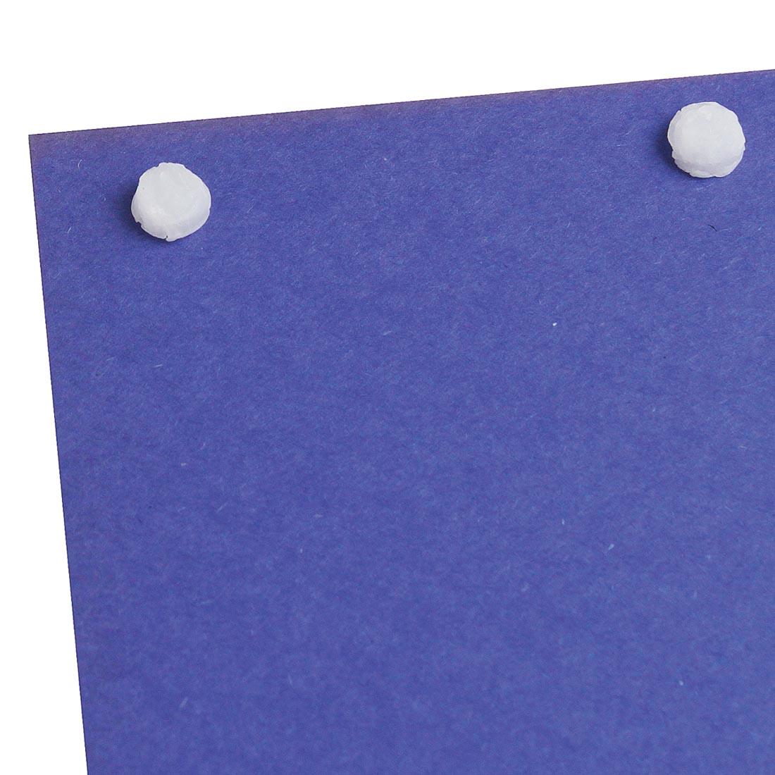Two StikkiWax Dots on a piece of purple paper