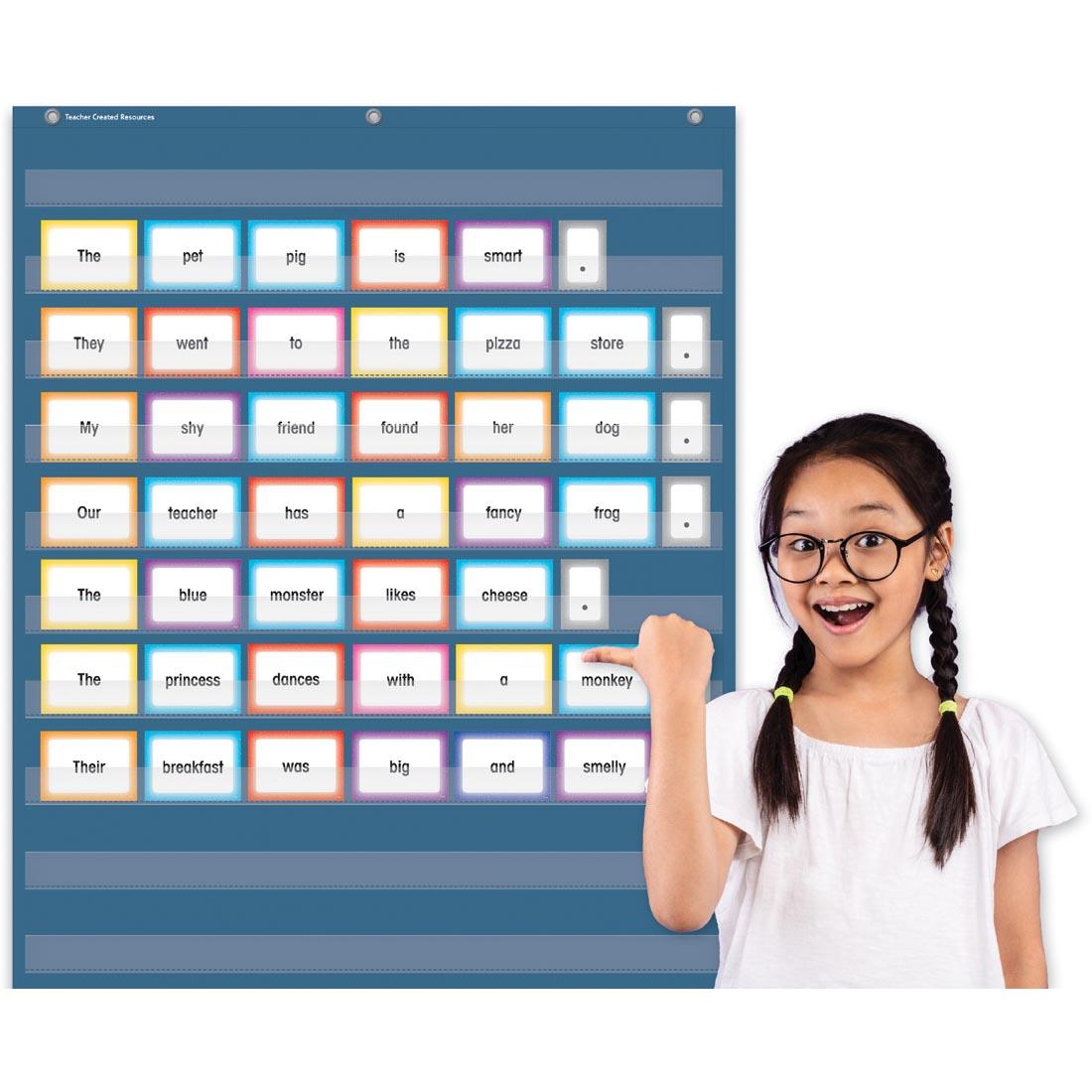 child next to the Slate Blue 10-Pocket Chart By Teacher Created Resources with cards in it