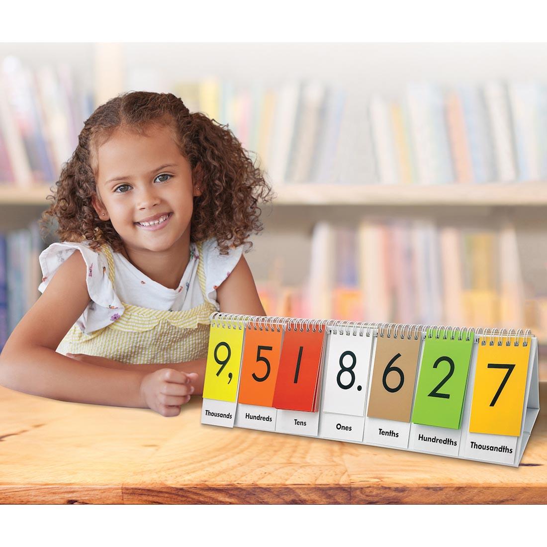 child sitting next to a Sensational Math Place Value Flip Stand By Teacher Created Resources