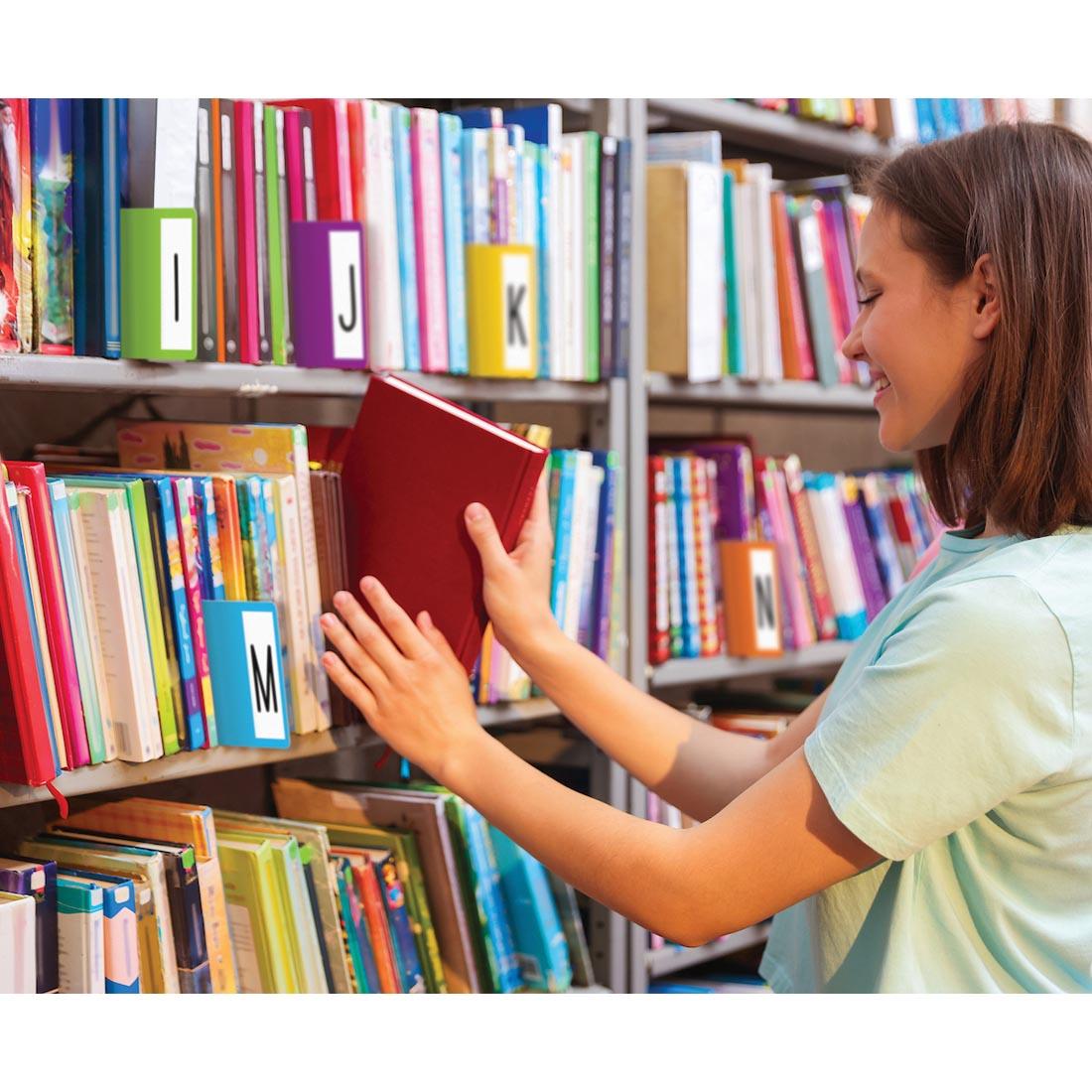 person using a bookshelf that contains Library Book Dividers By Teacher Created Resources in use