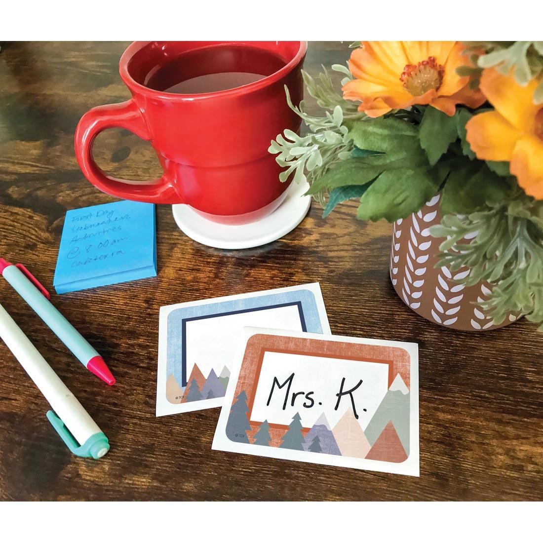 Two Name Tags/Labels from the Moving Mountains collection by Teacher Created Resources laying on a desk