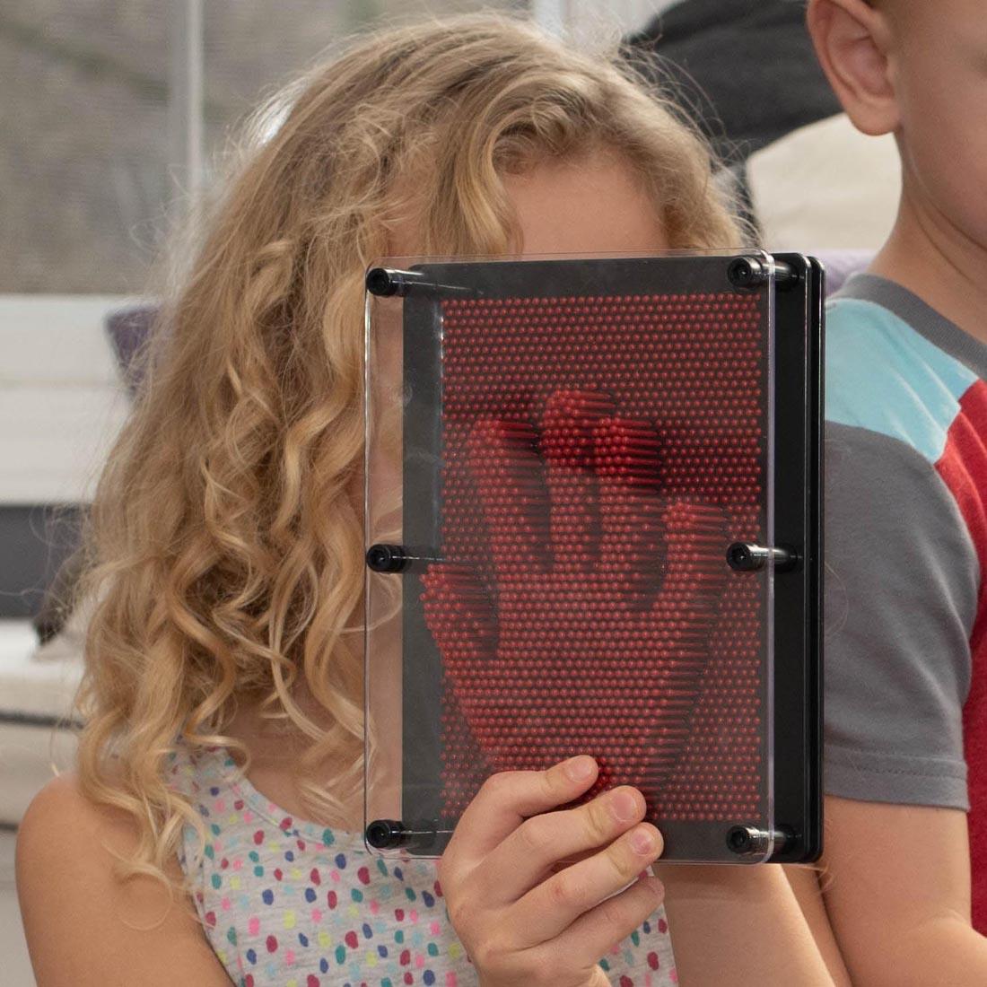 child pressing their hand into a Pin Art Relief Board
