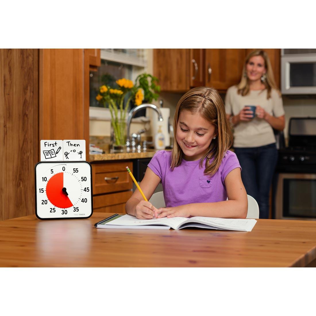 Child at a table with homework next to the Time Timer 8" Magnetic 60-Minute Timer