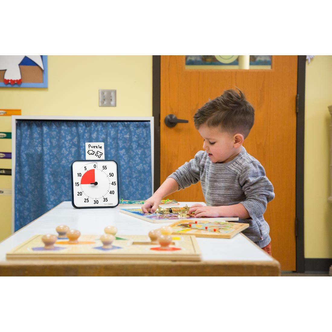 Child at a school puzzle table next to the Time Timer 8" Magnetic 60-Minute Timer