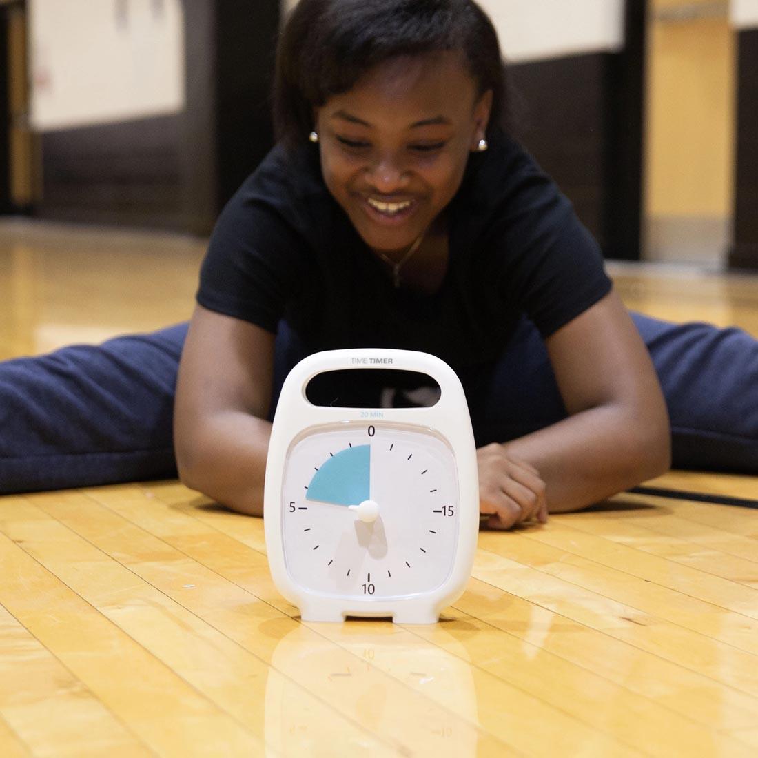 Child stretching on the gym floor next to the Time Timer PLUS 20-Minute Timer