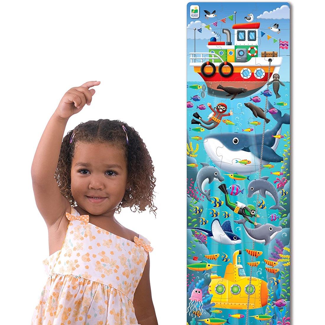 Child pointing to the completed Long & Tall Under The Sea Puzzle By The Learning Journey