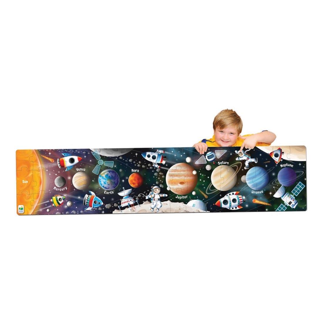 Child pointing to an astronaut on the completed Long & Tall Solar System Puzzle By The Learning Journey