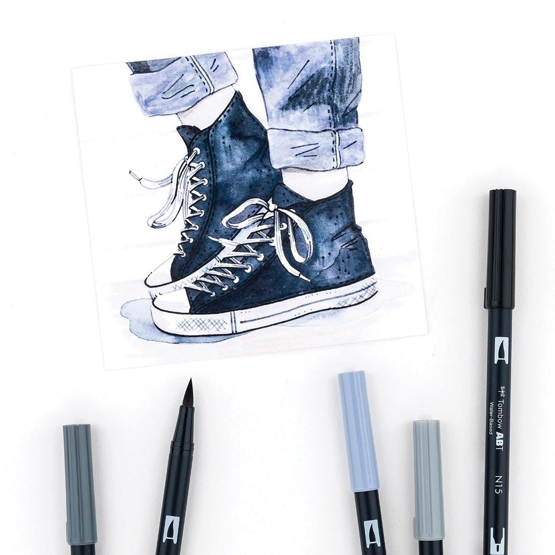 Several colors of Tombow Grayscale Dual Brush Pens laying on a drawing of sneakers